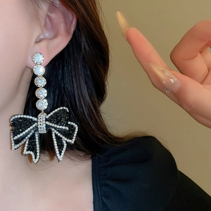 Detailed view of black and white bow earrings with sparkling cubic zirconia drops