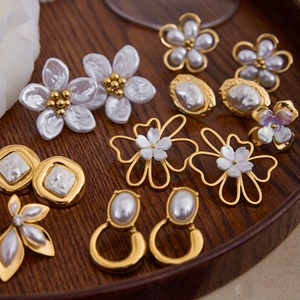 18K gold stainless steel earrings set with pearls and flower motifs on wooden tray