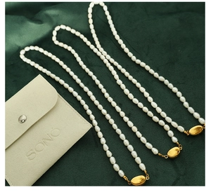 Close-up of freshwater pearl necklaces with gold oval clasps on green velvet background