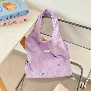 Macro view of lavender gingham fabric texture and colorful embroidered bows on canvas bag