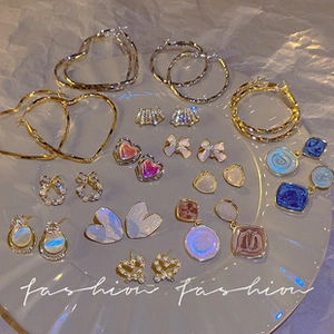 Flat lay close-up of a diverse mixed set of heart, pearl, and enamel earrings in soft tones