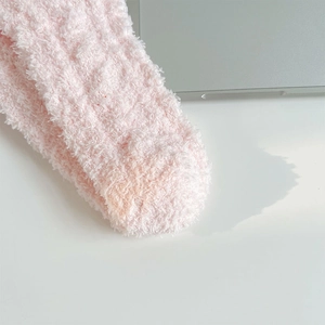 Gros plan sur la texture douce en polaire corail rose des chaussettes d'hiver
