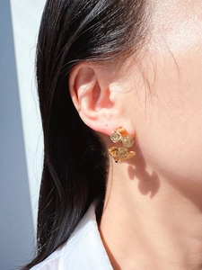 Close-up of golden vintage C-shaped coin earrings with textured relief on model