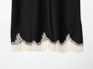 Detailed close-up of black satin hem with white eyelash lace trim and silky texture