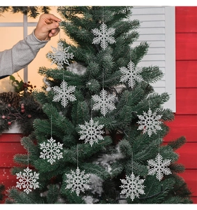 Silver glitter snowflake ornaments hanging on a Christmas tree with festive decoration