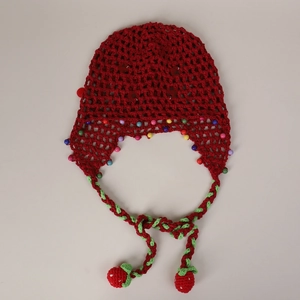 Detailed close-up of handmade red knit beanie with colorful beads and strawberry charms