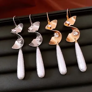 Twisted metal drop earrings with rhinestones and white pearls in gold and silver finish