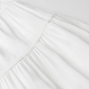 Gros plan d'une robe blanche élégante montrant une texture plissée et un tissu mousseline