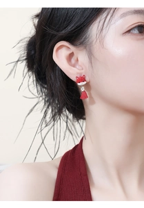 Close-up of red cartoon animal earrings with gold coin charms and silk tassels