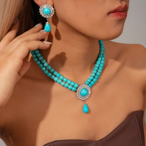 Detail of bohemian turquoise beaded double-layer necklace and matching drop earrings on model