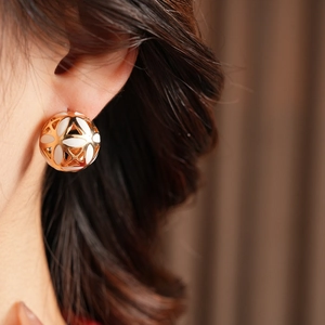 Gros plan de boucles d'oreilles vintage sphériques en or et émail blanc sur modèle