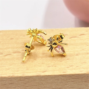 Macro view of gold spider earrings featuring micro-pave pink teardrop gemstones