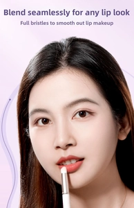 Close-up of portable round head lip brush blending lipstick on lips with silver ferrule