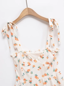 Détail de l'imprimé orange et des bretelles nouées sur cette robe d'été blanche