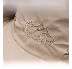 Detailed embroidery of mountains and Travellers text on light khaki outdoor hiking cap
