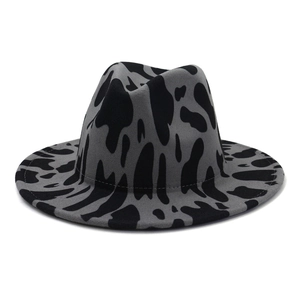 Detailed view of gray fedora hat with black cow pattern and wide brim stitching