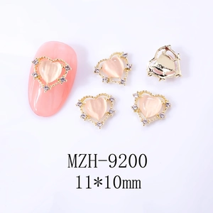 Charm ongle cœur œil de chat rose avec bord doré ajouré et détails en zircone cubique