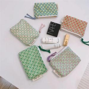 Flat lay of small floral cotton pouches with zipper and woven puller on white surface