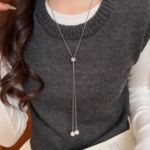 Détail d'un collier pull argenté en Y avec pendentif en zircon et doubles perles