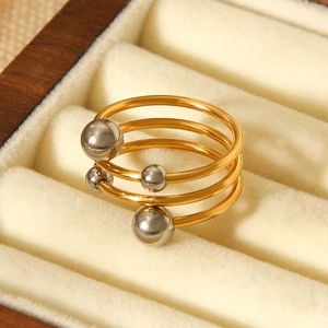 Three-layer stainless steel wrap ring with gold bands and silver beads on velvet