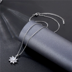 Close-up of a silver flower necklace with marquise-cut crystals on a textured gray base