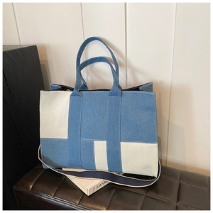 Close-up of blue and white denim patchwork tote bag on black leather bench in studio