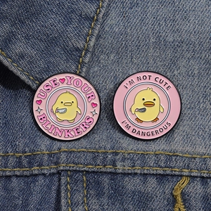 Detailed close-up of cute yellow duck enamel pins on denim jacket showing creative text