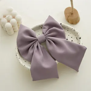 Detailed view of elegant purple fabric bow hairclip on a marble plate with candles