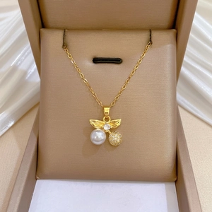 Elegant gold cherry necklace with lustrous pearl and crystal sphere in a jewelry box