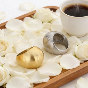 Close-up of gold and silver thick round rings on a wooden tray with white roses