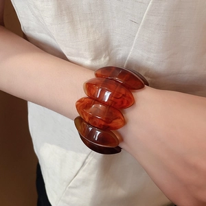 Detailed view of amber resin chunky bangle featuring wavy texture and gradient tones