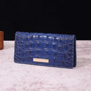 Detail of blue crocodile-embossed leather wallet with elegant gold metal trim