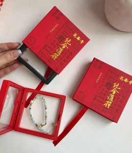 Vista detallada de pulsera de cuentas de colores con dijes dorados y caja de regalo