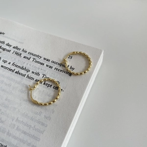 Elegant 925 sterling silver gold beaded hoop earrings placed on an open book