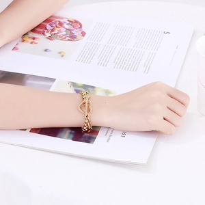 Double heart charm gold bracelet with thick link chain worn by fashion model