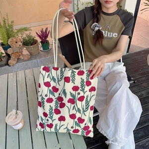 Gros plan détaillé d'un grand sac cabas en toile avec des motifs floraux rouges au café