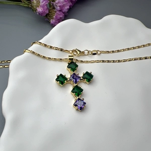 Golden cross necklace with green and purple square zircons on an elegant bamboo chain