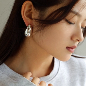 Close-up of a polished silver teardrop earring showing smooth mirror-like finish and texture