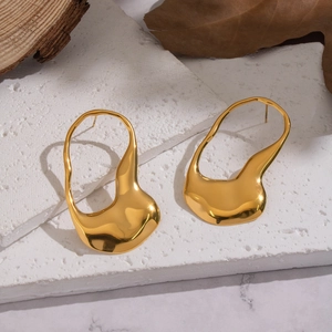Detail view of irregular geometric gold earrings with polished mirror finish on a stone