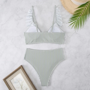 Green and white striped bikini with ruffled straps and high-waisted bottom on marble
