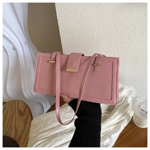 Detail of pink faux crocodile leather texture and gold metal buckle on a square handbag