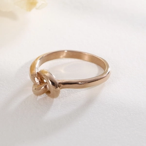 Detail shot of a polished rose gold knot ring featuring an elegant twisted design