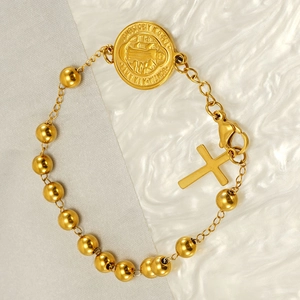 Macro detail of a gold stainless steel St. Benedict medal and cross on a beaded bracelet