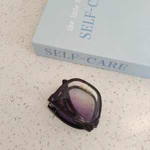 Foldable UV400 children sunglasses with purple gradient lenses on a marble surface