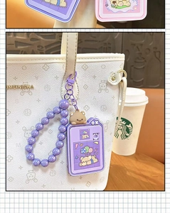 Detail showing a cute purple bear sliding puzzle keychain attached to a stylish white tote bag
