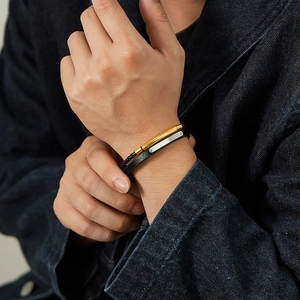 Gros plan de bracelets en cuir pour hommes avec barres en métal or et argent au poignet