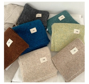 Detail showing various solid color knitted wool blend scarves with egg brand labels