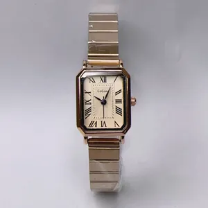 Detail shot of rectangular rose gold watch dial with Roman numerals and metal link strap