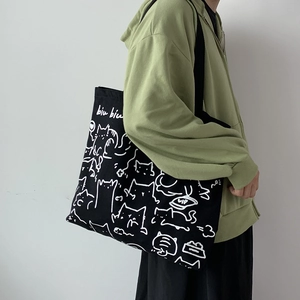 Detail of black canvas tote bag with hand-drawn cat illustration and biu biu lettering