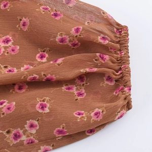 Detail of floral chiffon blouse with elastic cuffs and purple floral print on brown fabric